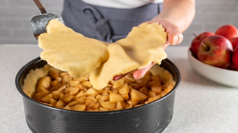 Putting top crust on pie