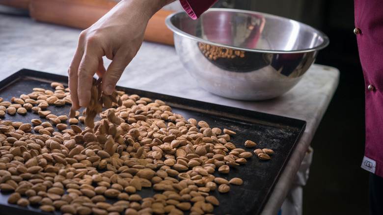 person toasting almonds on sheet pan