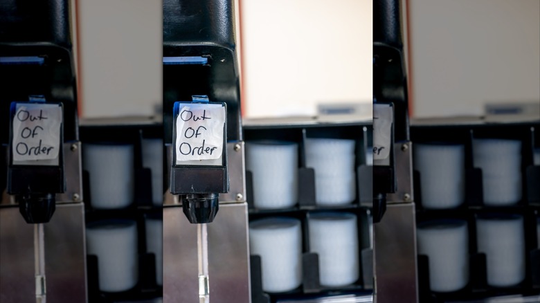 Out of order sign on broken milkshake machine with shelf of lids in background