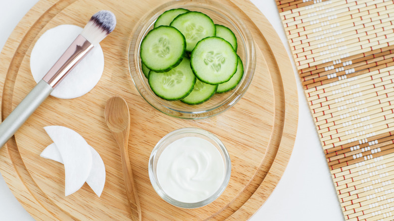 Paint brush, cucumbers, a spoon, and yogurt on a tray