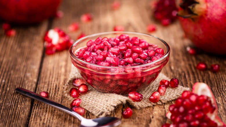 a bowl of pomegranate seeds on a wooden table