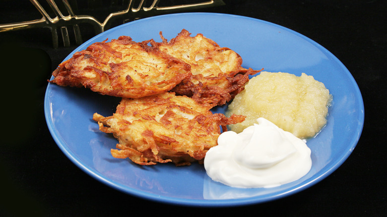 a plate of latkes and sour cream and applesauce