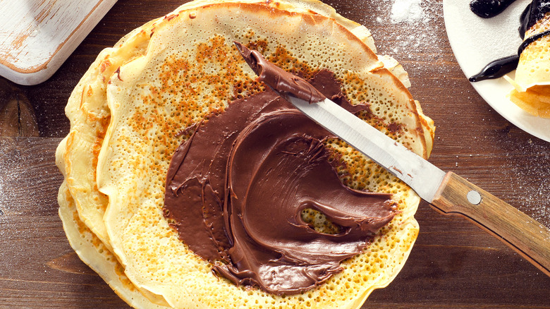 Knife spreading nutella on crepes