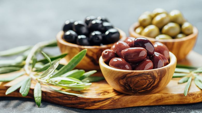 three wooden bowls with olives