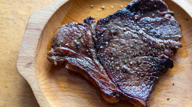 Well-done steak on wooden plate