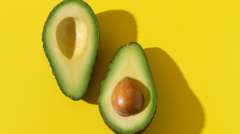 2 avocado halves on yellow background