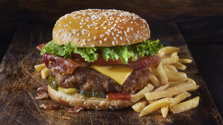 bacon cheeseburger and fries on wood