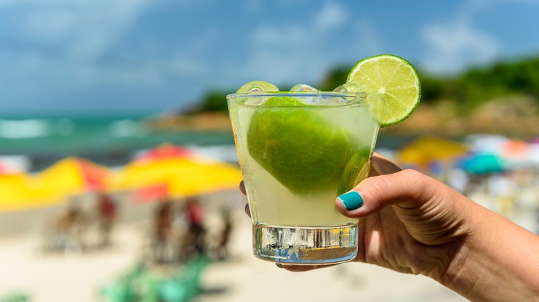 Hand holding Caipirinha at beach