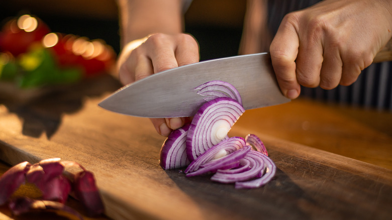 person slicing onions on board