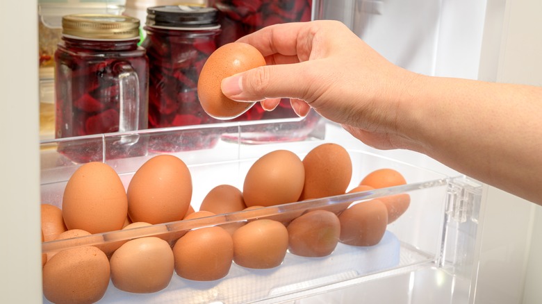 Hand taking egg from fridge