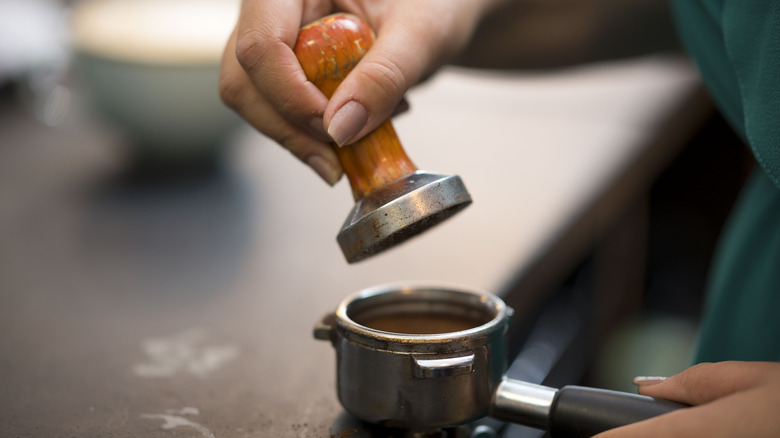 a woman tamps down the espresso beans