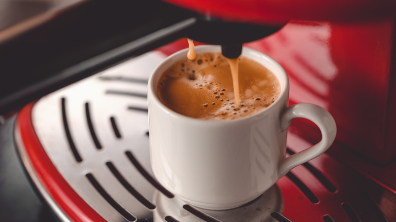 espresso drips from a red countertop machine