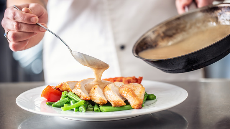 pouring sauce on sliced chicken