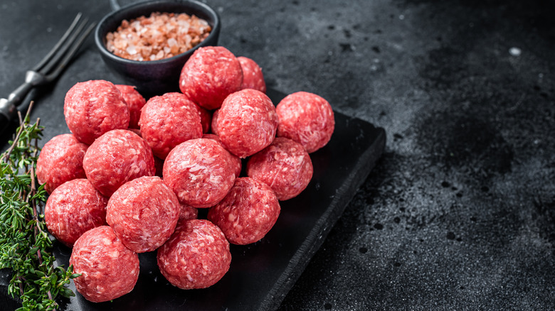 Uncooked meatballs on black background