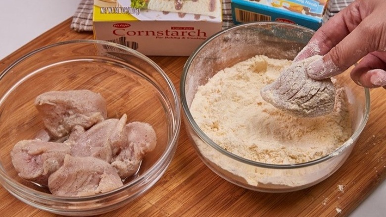 Dredging chicken in bowl of cornstarch