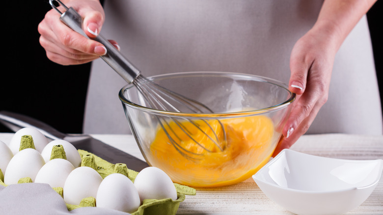 person whisking eggs in bowl