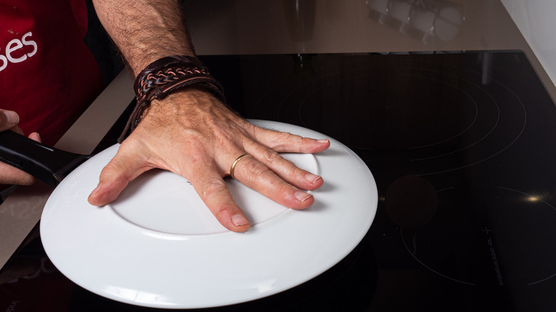 hand holding plate over pan