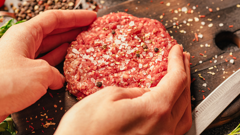 person making and seasoning hamburgers