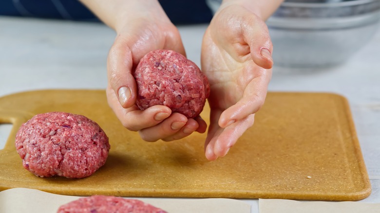 person making burgers by hand