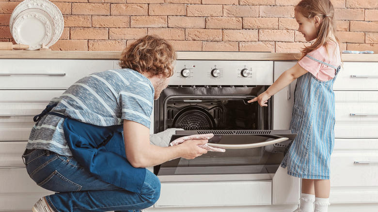 Father and daughter opening oven