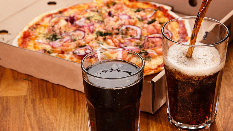 Two sodas next to pizza