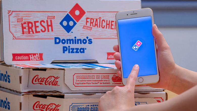 Holding phone near Domino's boxes