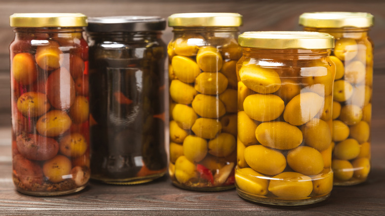 Jars of olives on a wooden surface