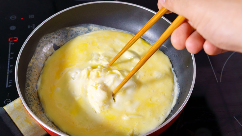 Person mixing omelet with chopsticks