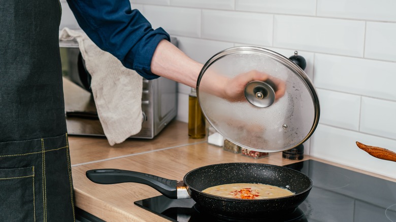 Person lifting lid from omelet