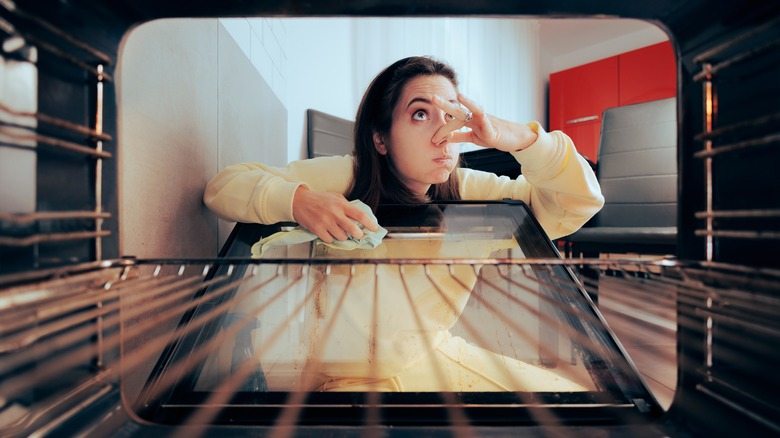 woman cleaning smelly oven