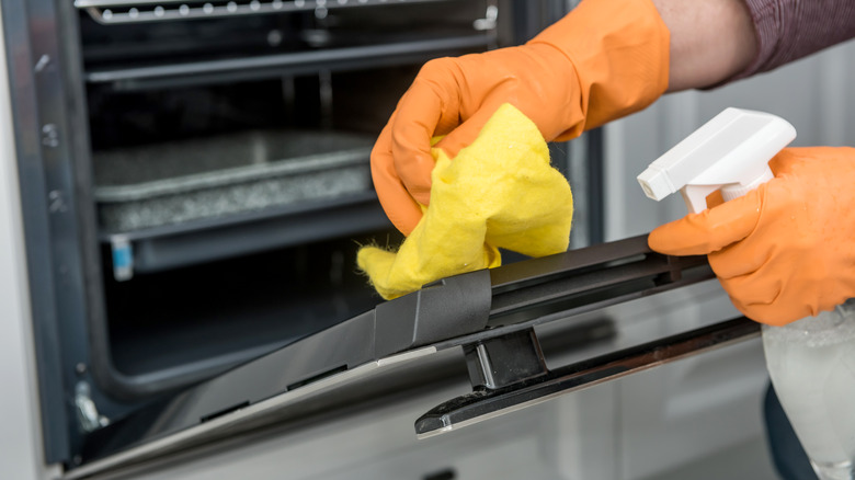 person cleaning oven with chemicals