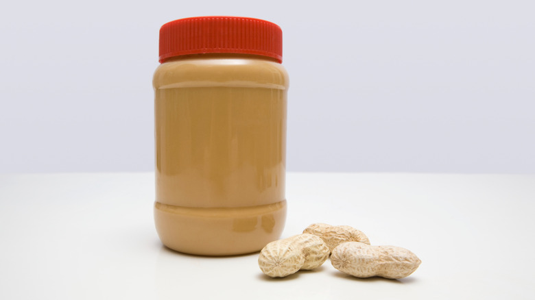 Unlabeled jar of peanut butter with unshelled peanuts