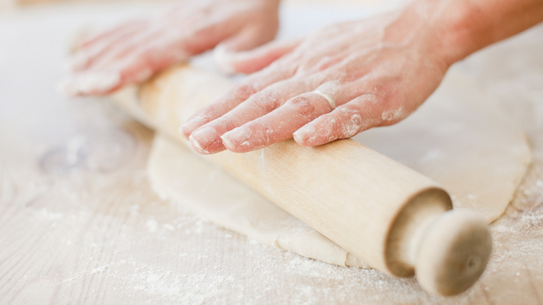 Hands rolling out dough