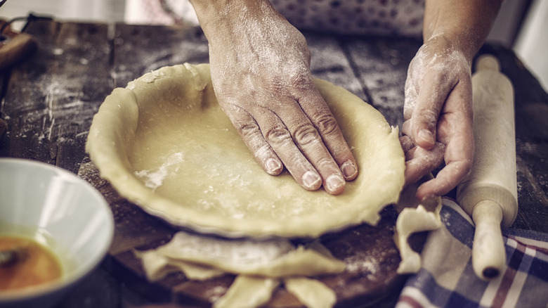 Floured hands patting pie crust