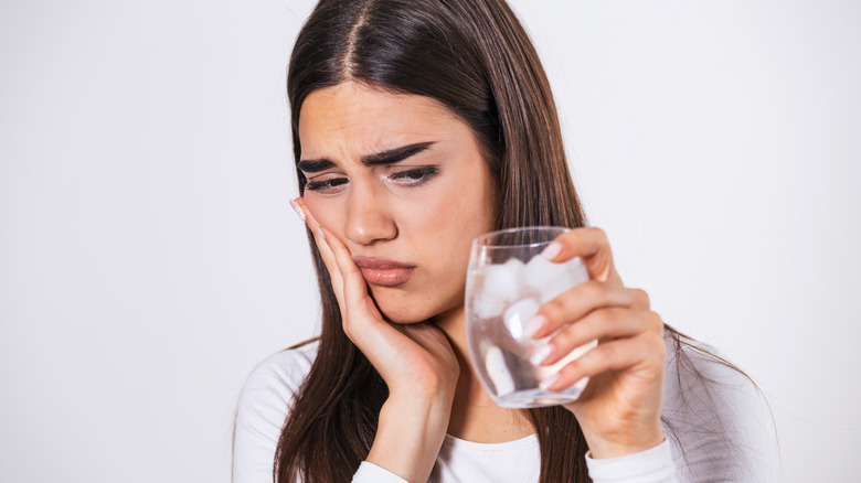 woman grimacing holding ice water