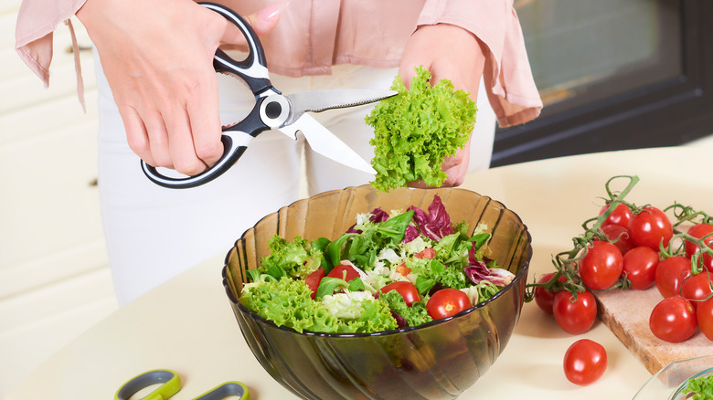 person using scissors to prepare salad