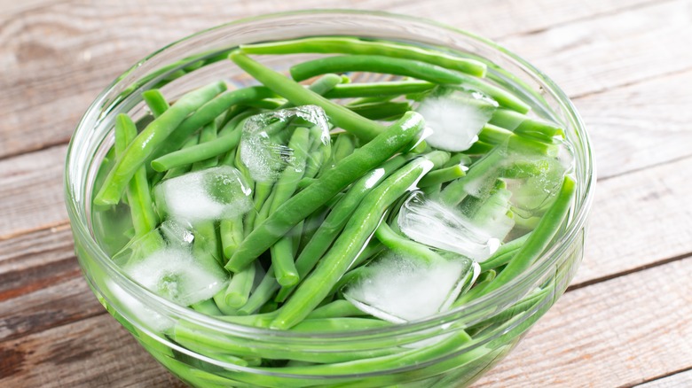 blanched green beans in bowl of ice water