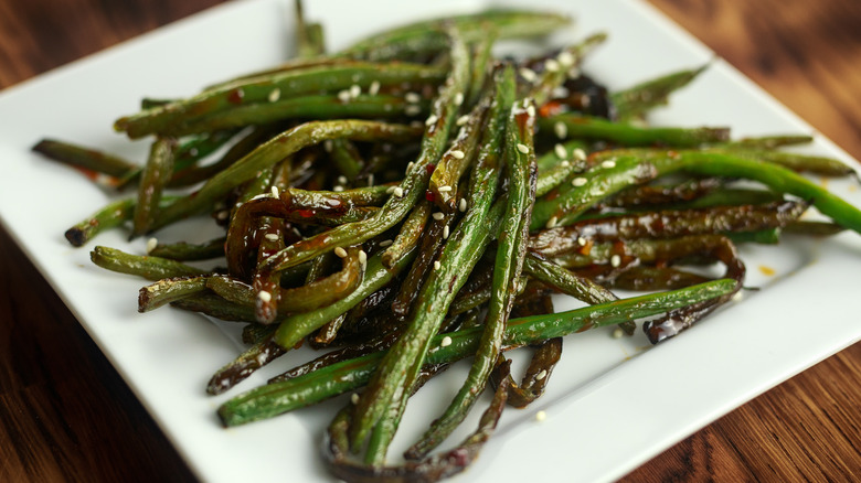 stir-fried green beans with sesame seeds on a white plate