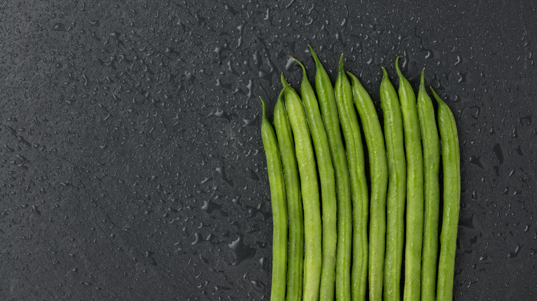 line of green beans on black slate background