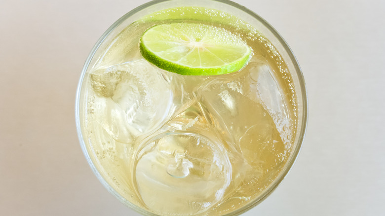 Topdown view of glass of ginger ale, with lime slice floating