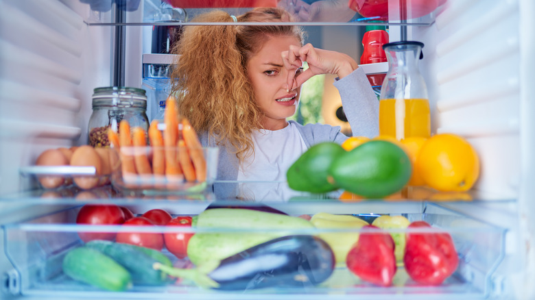 woman holding nose by fridge