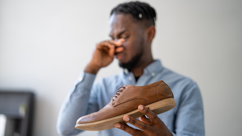 man holding stinky shoe