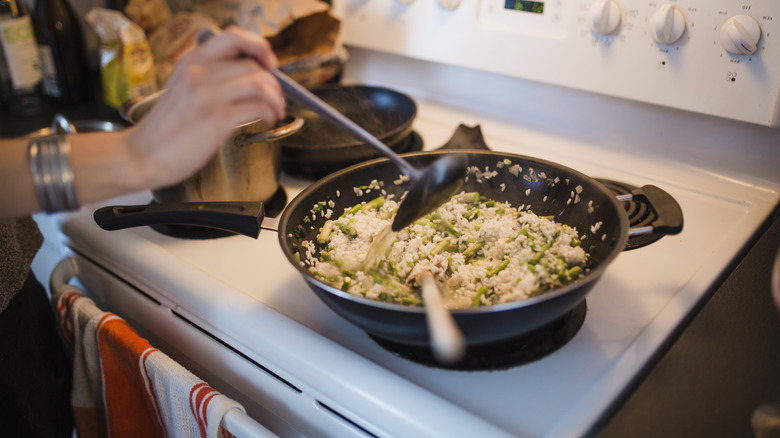 person adding stock to risotto