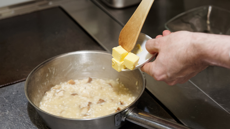 person adding butter to risotto