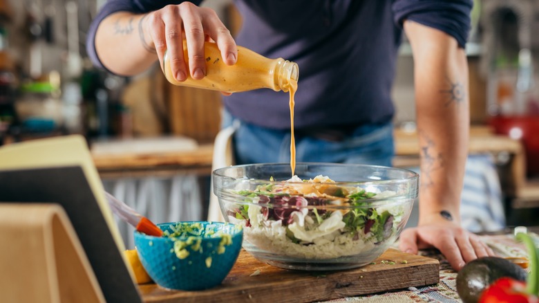 Cook pouring dressing on salad