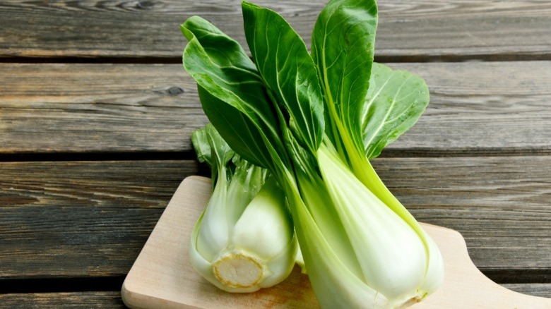 Two whole large bok choy on cutting board