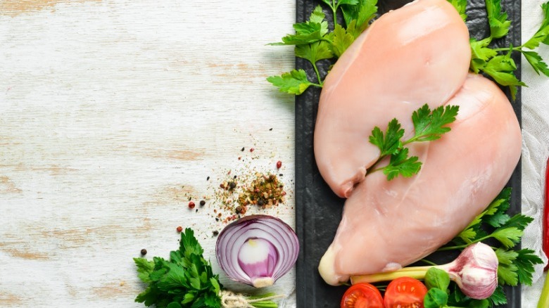 Raw boneless chicken breasts with parsley