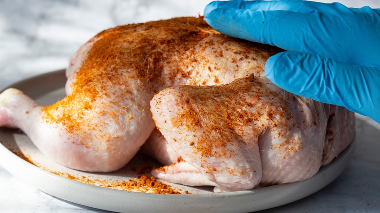 hand rubbing spices on chicken