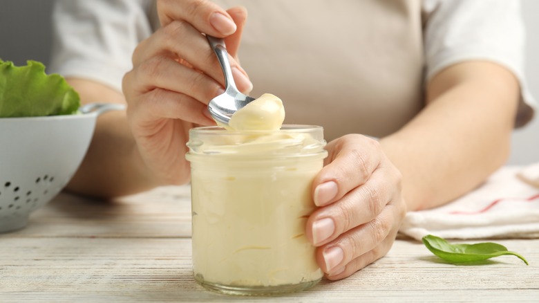 person spooning jar of mayonnaise