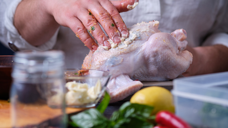 hand rubbing butter on chicken